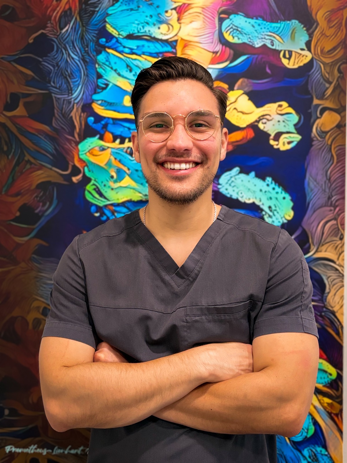 Dr. Sebastian Requena smiling in chiropractic scrubs